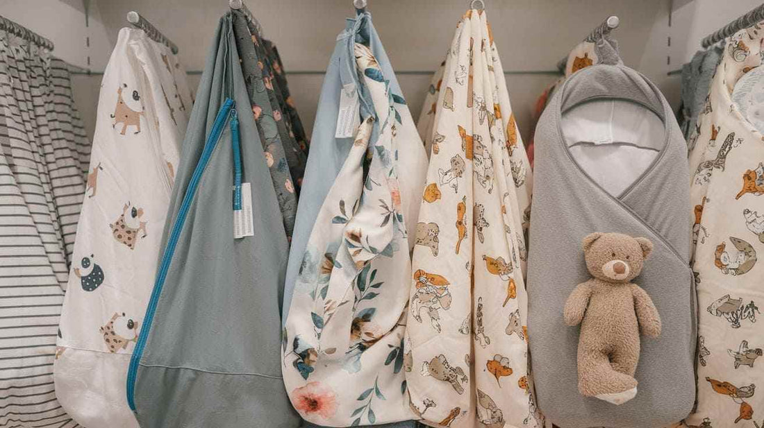 various sleep sacks and swaddles in a store. There are swaddles with different patterns, including stripes, flowers, and animals.