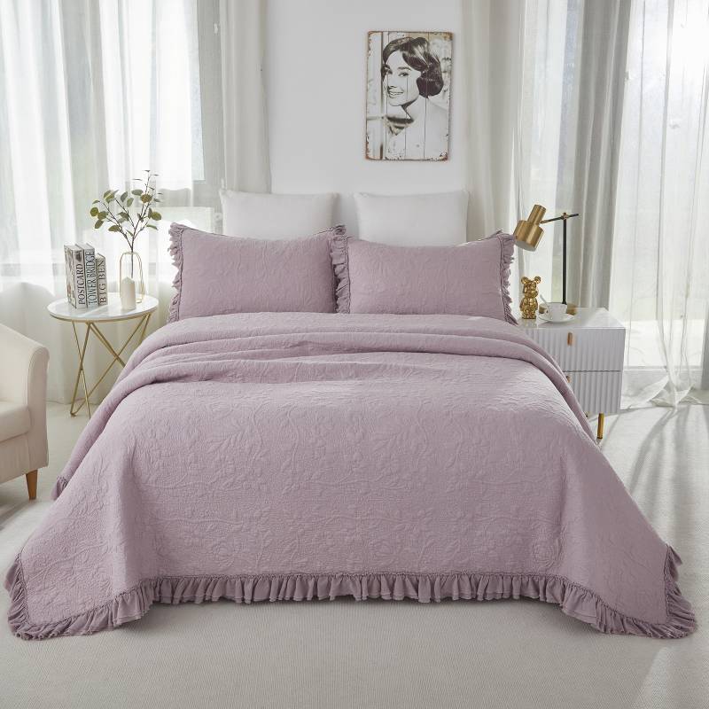 a purple quilt in a light bed room