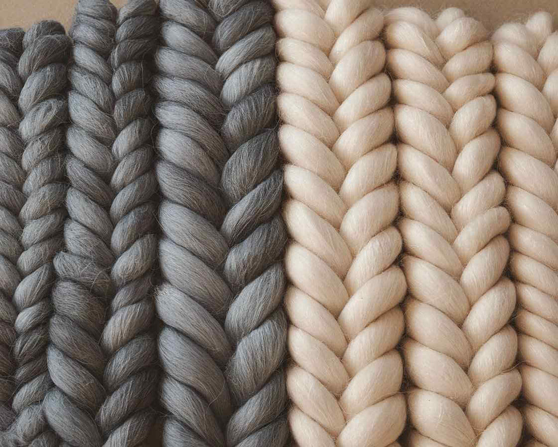 A photo of cashmere and wool fibers. Cashmere fibers are shown in a darker shade of grey and wool fibers in a lighter shade of grey. 