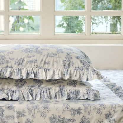 Bed with green floral patterned bedding and pillows on a neutral background
