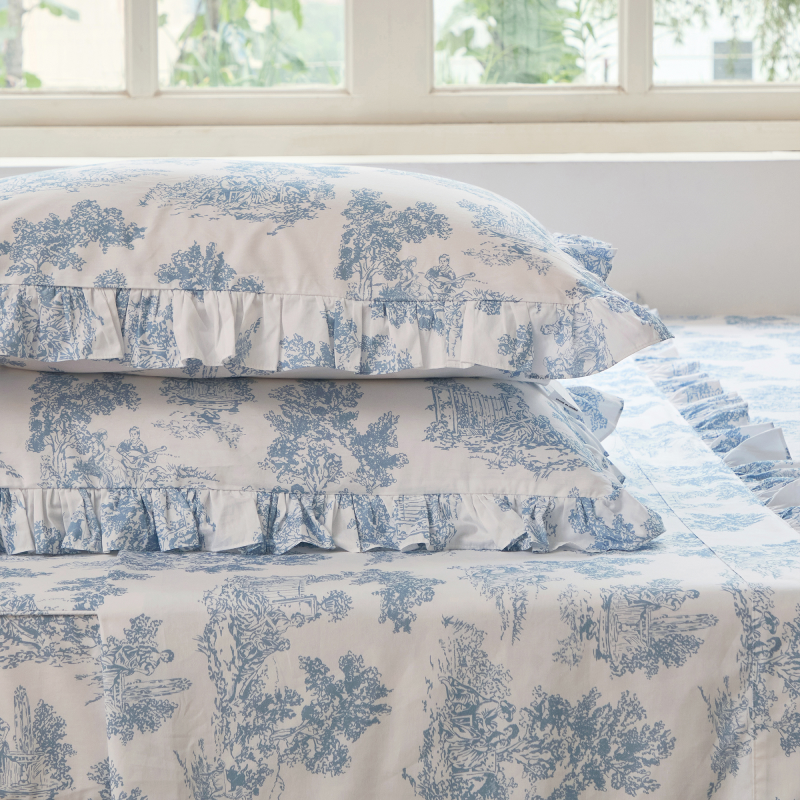 Bed with green floral patterned bedding and pillows on a neutral background
