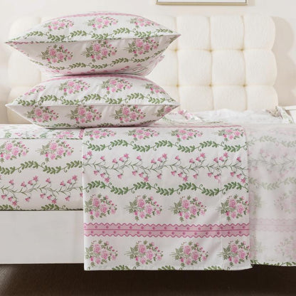 Bed with green floral patterned bedding and pillows on a neutral background