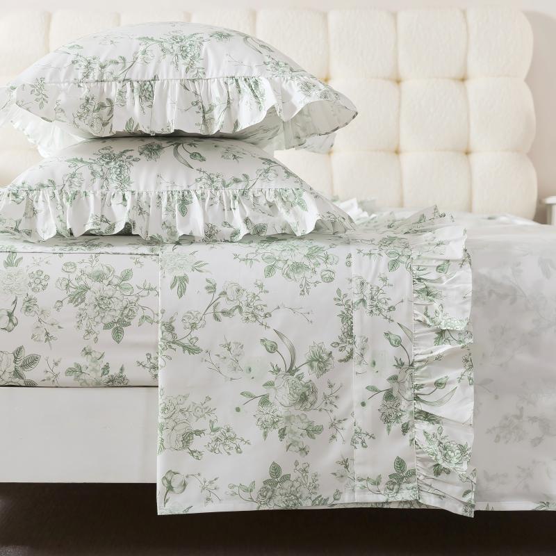 Bed with green floral patterned bedding and pillows on a neutral background