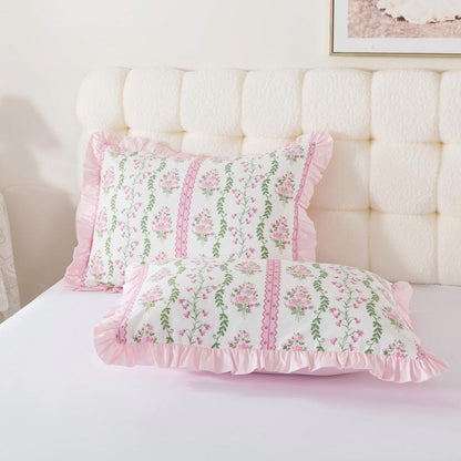 Floral-patterned pillows on a bed with candles in the background