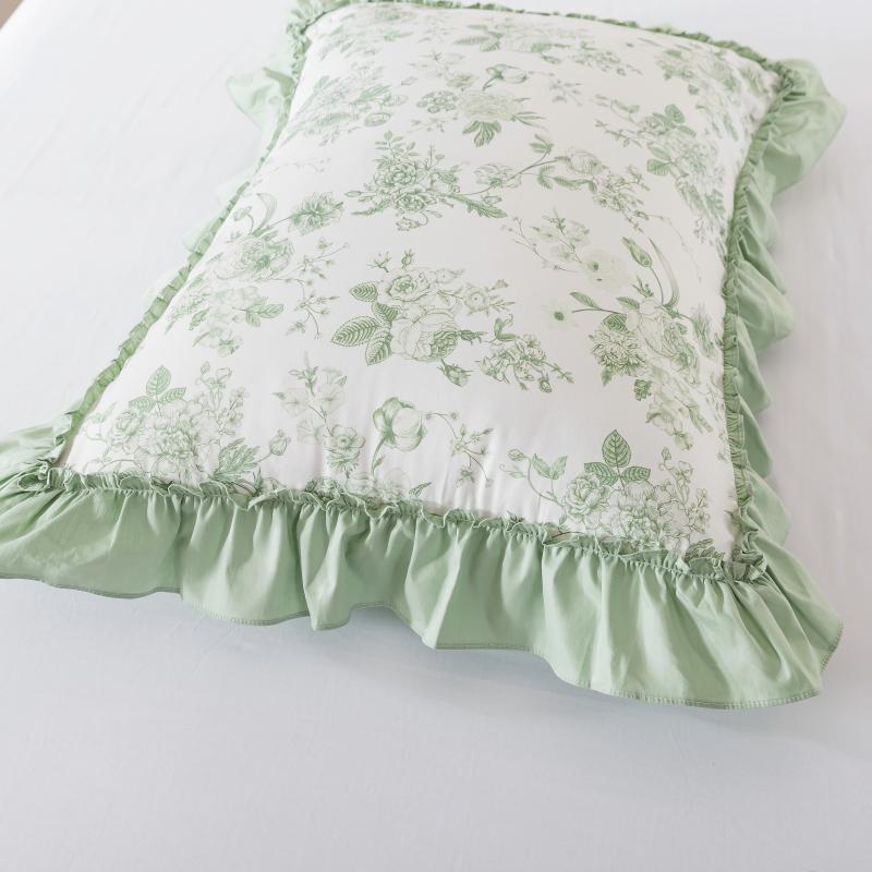 Floral-patterned pillows on a bed with candles in the background