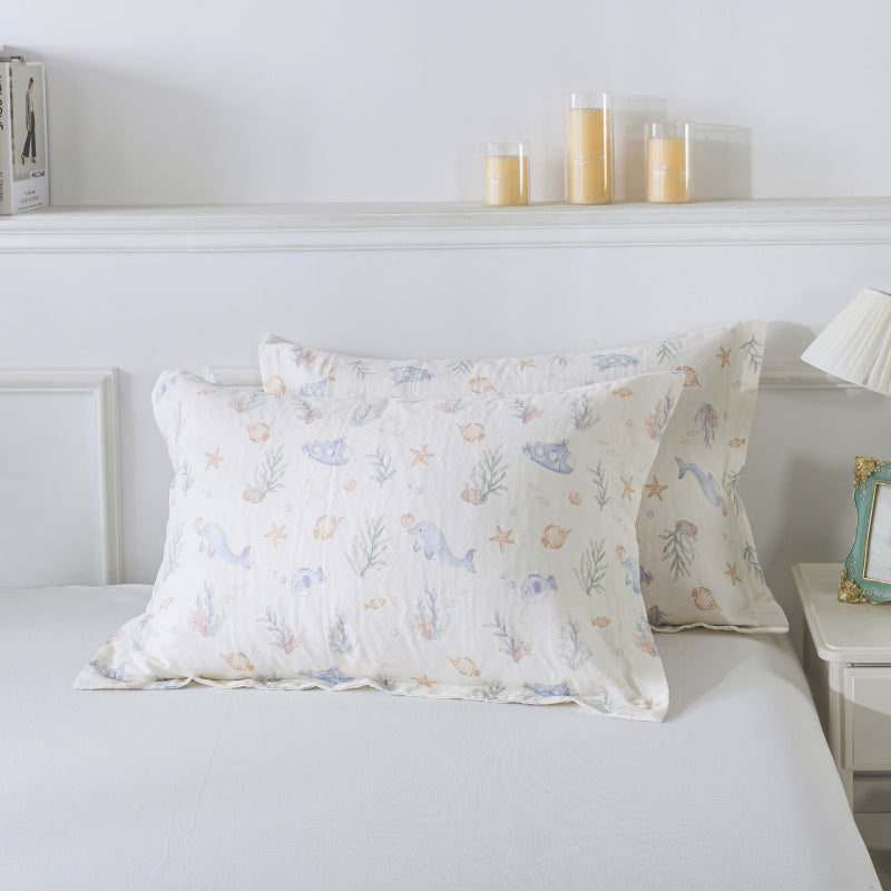 Decorative pillows with a sea-themed pattern on a bed in a bedroom setting.