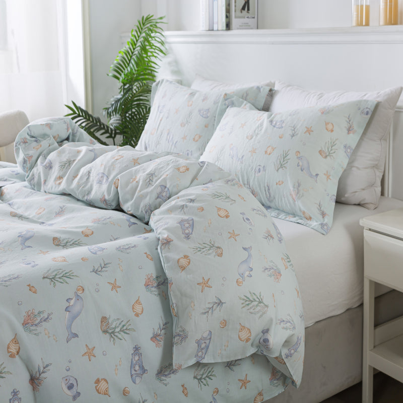 Bed with light blue floral and animal patterned bedding in a bright bedroom.
