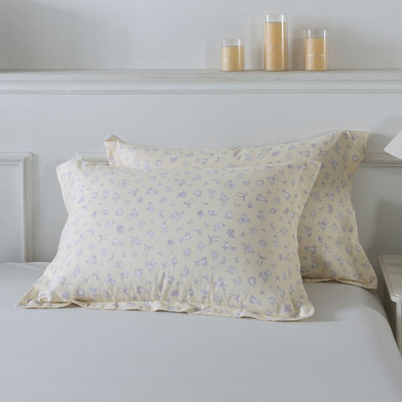 Floral-patterned pillows on a bed with candles in the background